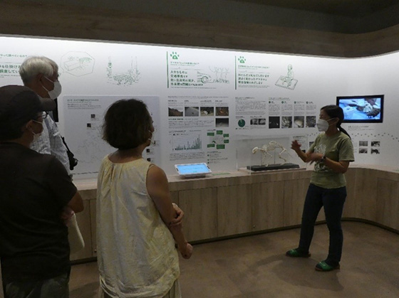 A lecturer giving an explanation of the exhibition and a participant listening to it.
