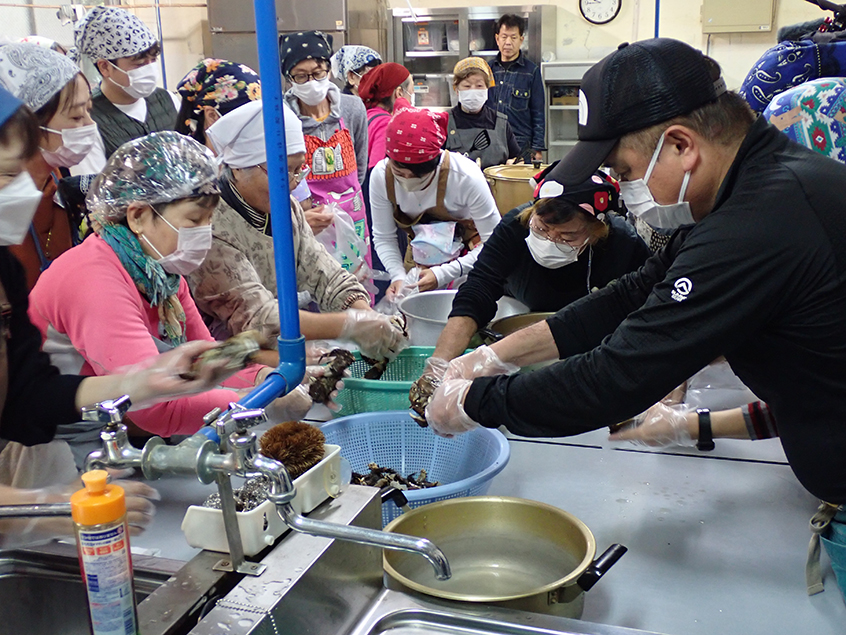 地域の方による指導の下、カニの殻から身と卵を取り出す作業を行いました